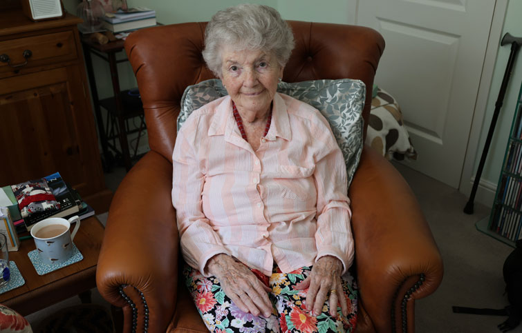 Kay is sitting in a chair smiling at the camera