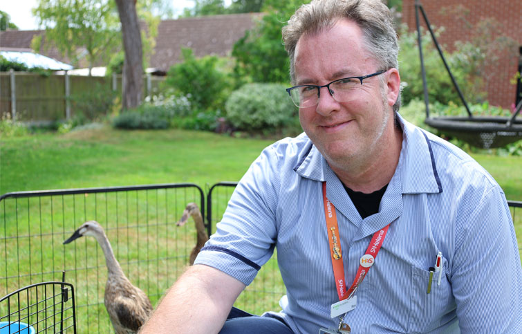 Nurse Rick in the St Helena Hospice garden with running ducks behind him