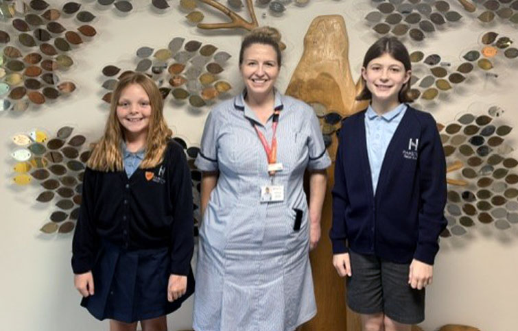 Two ten year old girls visited St Helena Hospice to write an article for the newspaper, here they are pictured with nurse Holly