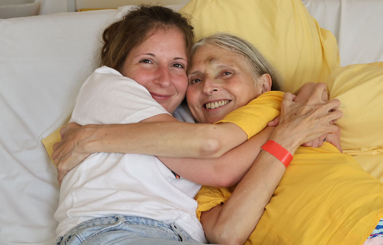 Anna and Catherine hugging on the cuddle bed at St Helena Hospice