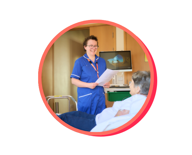 A St Helena nurse smiling whilst talking to a patient who is in bed at the hospice
