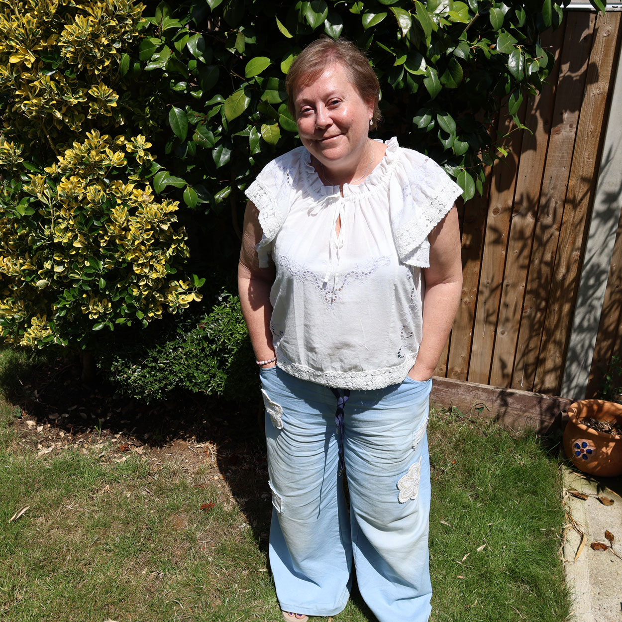 Wendy is standing in a garden and smiling at the camera