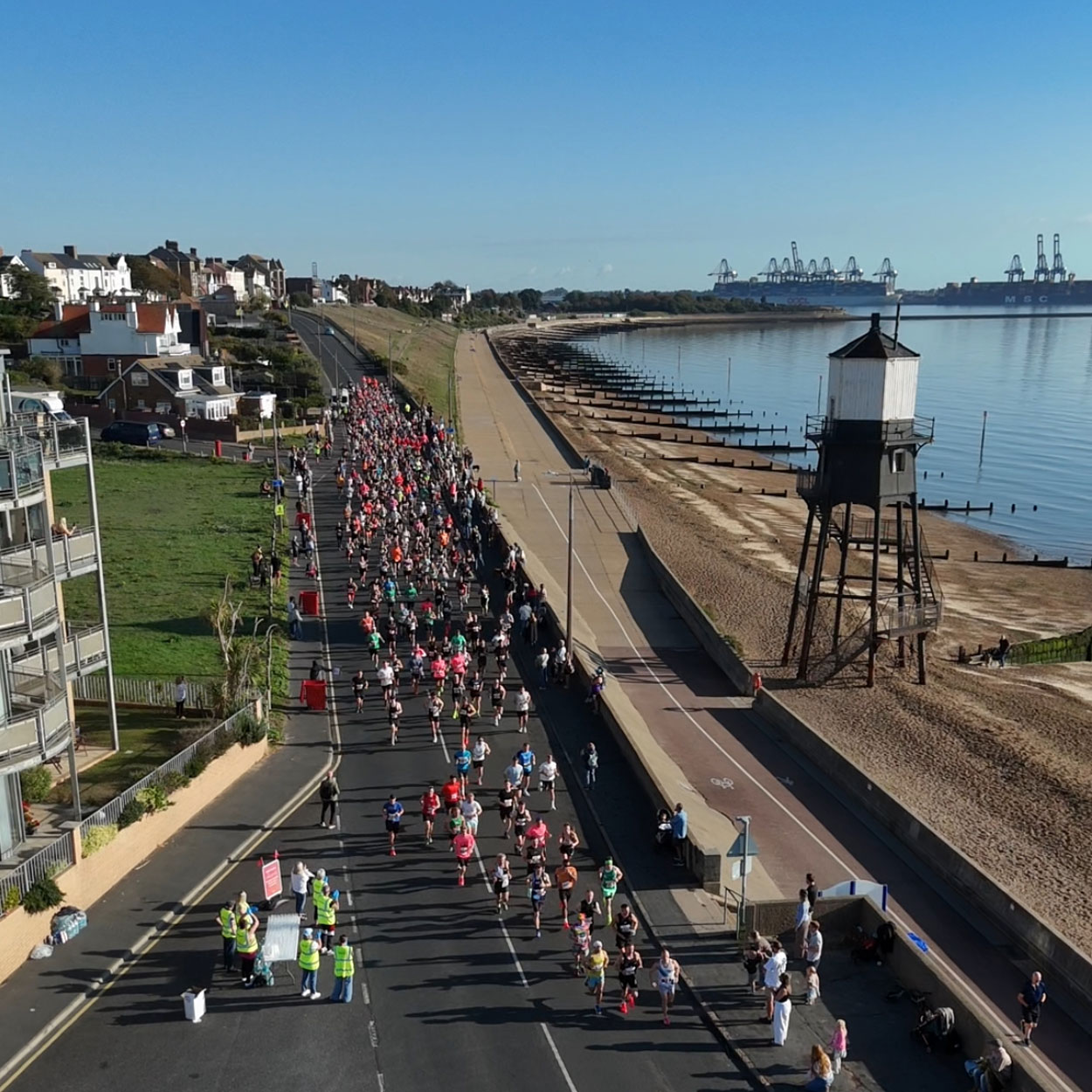 Runners along the seafront with Dovercourt lighthouse in view for St Helena Hospice Harwich Half Marathon
