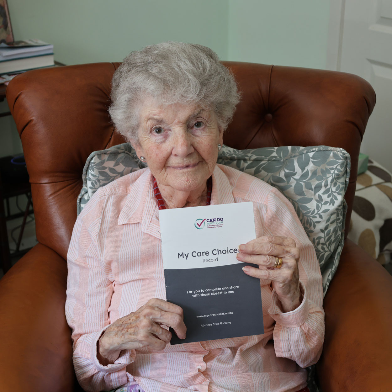 Kay sitting in a chair holding the My Care Choices Record